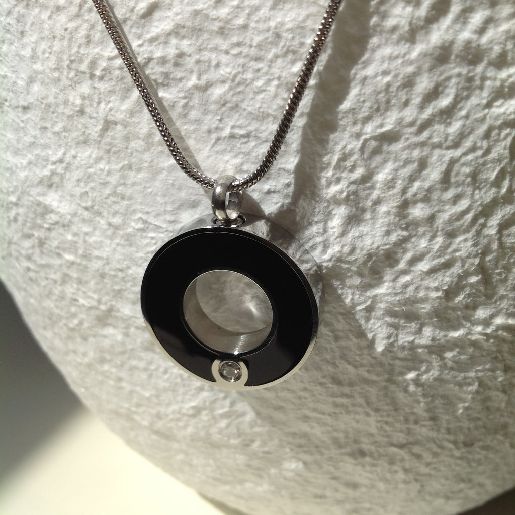 Picture of a Stainless Steel  cremation jewelry with a round pendant for ashes - white background